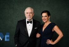 Brian Cox and Nicole Ansari-Cox posing together in elegant formal attire at a red carpet style event.