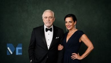 Brian Cox and Nicole Ansari-Cox posing together in elegant formal attire at a red carpet style event.