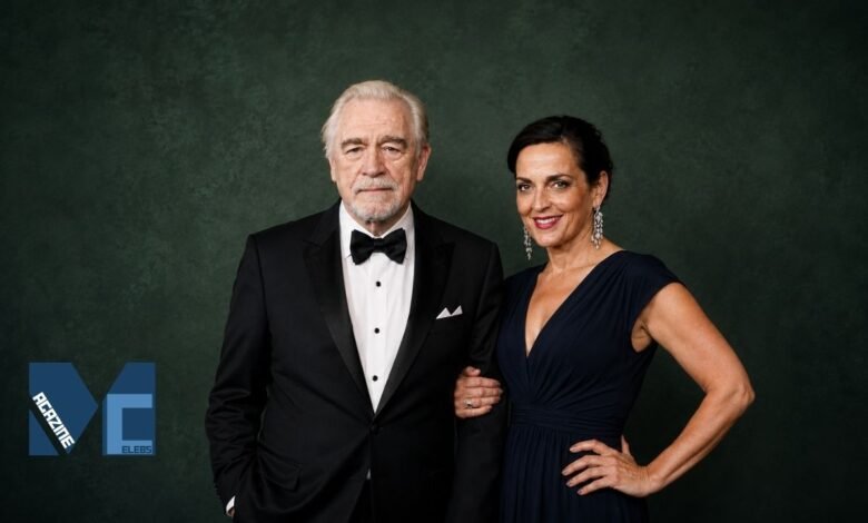 Brian Cox and Nicole Ansari-Cox posing together in elegant formal attire at a red carpet style event.