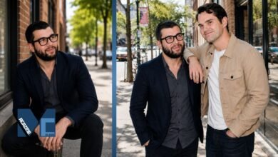 Colin Carr wearing a navy blazer and thick glasses alongside his comedian brother Jimmy Carr on a city street.