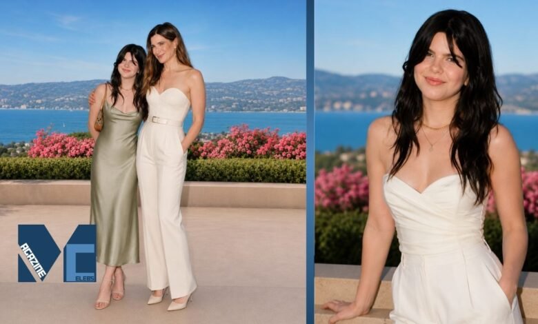 Mae Sandler posing alongside her mother Kathryn Hahn at an outdoor coastal event with scenic ocean views and floral surroundings.