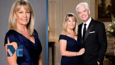 Stephanie Lowe posing in an elegant navy blue dress during a formal portrait session with her husband.