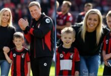 Vicki Howe smiling with her husband Eddie Howe and their children on the football pitch wearing AFC Bournemouth kits.