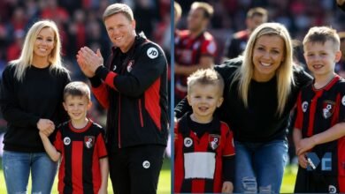 Vicki Howe smiling with her husband Eddie Howe and their children on the football pitch wearing AFC Bournemouth kits.