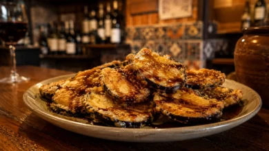 A premium close-up shot of crispy golden berenjenas con miel drizzled with dark sugarcane molasses on a rustic plate, perfect for finding the best Andalusian tapas near you.