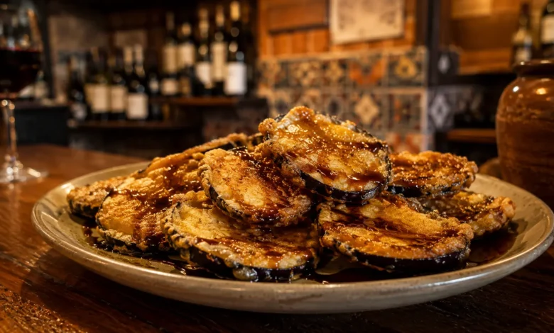 A premium close-up shot of crispy golden berenjenas con miel drizzled with dark sugarcane molasses on a rustic plate, perfect for finding the best Andalusian tapas near you.
