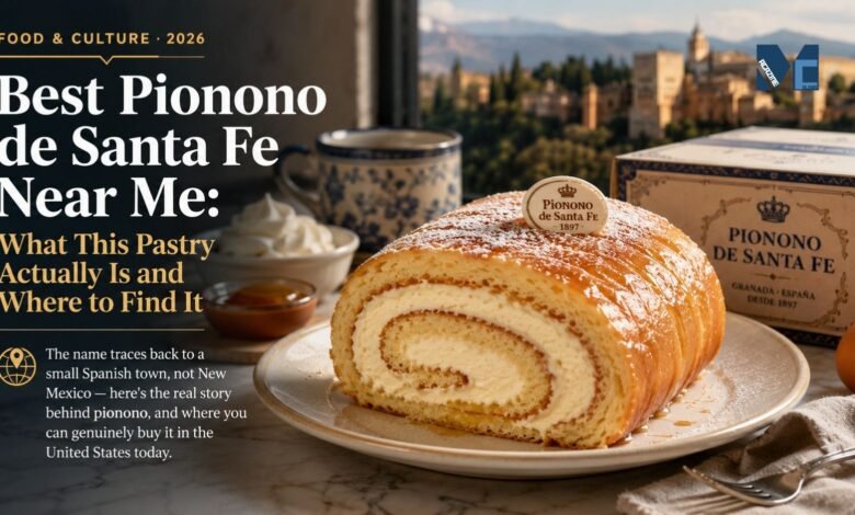 A traditional Pionono de Santa Fe rolled sponge cake filled with cream and topped with toasted sugar, served on a plate with a vintage bakery box and the city of Granada in the background.