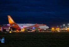 EasyJet Airbus A320 parked on a runway at night surrounded by ambulances and airport fire vehicles during an emergency response at Newcastle Airport.