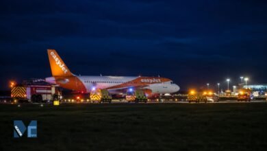 EasyJet Airbus A320 parked on a runway at night surrounded by ambulances and airport fire vehicles during an emergency response at Newcastle Airport.