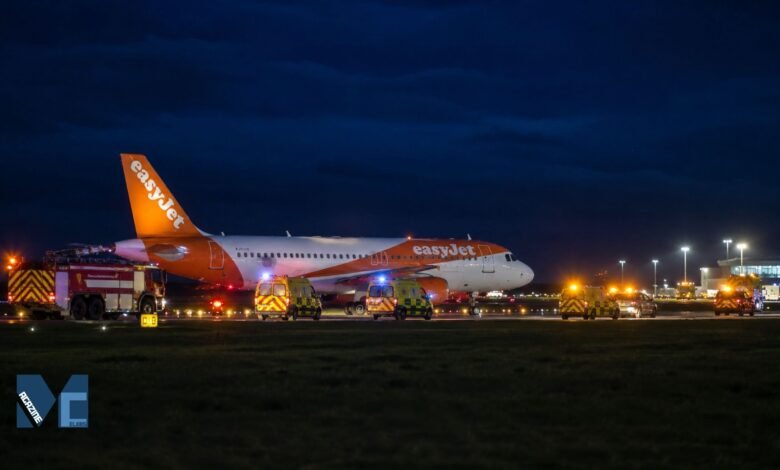 EasyJet Airbus A320 parked on a runway at night surrounded by ambulances and airport fire vehicles during an emergency response at Newcastle Airport.