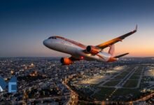 A commercial passenger jet climbing over an illuminated city and airport at dusk, representing the EasyJet flight U24429 emergency departing from Lyon.