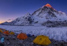Everest Advanced Base Camp at dawn with colorful expedition tents, East Rongbuk Glacier ice formations, and the illuminated north face of Mount Everest in Tibet.