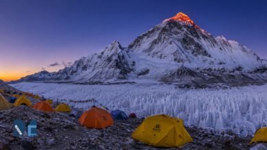 Everest Advanced Base Camp at dawn with colorful expedition tents, East Rongbuk Glacier ice formations, and the illuminated north face of Mount Everest in Tibet.
