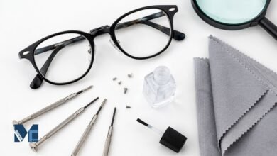 Eyeglass repair kit showing precision screwdrivers, spare screws, nail varnish, microfibre cloth, and glasses on a white surface for fixing loose eyeglasses at home.