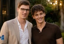 Litigation attorney Fielder Jewett in a beige blazer and glasses standing next to his husband, actor Hunter Doohan, smiling at an outdoor evening event.