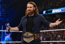 Sami Zayn holding a WWE championship during an arena appearance in 2026.