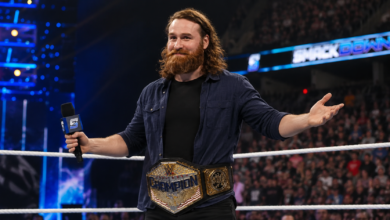 Sami Zayn holding a WWE championship during an arena appearance in 2026.