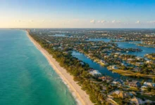 An aerial panoramic view of the beautiful Southwest Florida coastline within the 239 area code region, showing luxury waterfront properties, white sand beaches, and deep blue Gulf waters.