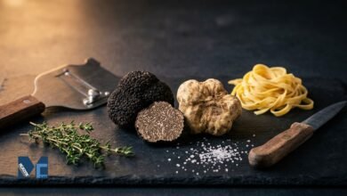 Black Périgord truffle and white Alba truffle displayed with fresh pasta and a truffle shaver.