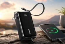 Black Anker 3-in-1 30W Fusion power bank with a digital display, foldable plug, and built-in USB-C cable charging an iPhone.